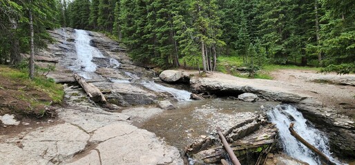 Narrow waterfall flowing over the rocks in Ouray, Colorado surrounded by fir forest trees