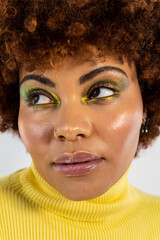 A vertical photo of a close-up of a portrait of a dark-skinned girl with afro hair on a white background. The girl looks to the side with a serious expression. Concept of African woman.