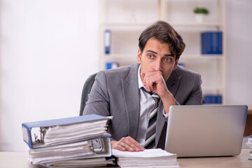 Naklejka premium Young male employee unhappy with excessive work in the office