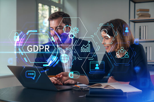 Thoughtful businesspeople typing on laptop at office workplace. Concept of team work, business education, internet surfing, brainstorm, project information technology. GDPR hologram