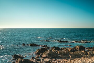 Scenic shot of a rocky coastline and the horizon on the other part of the blue sea