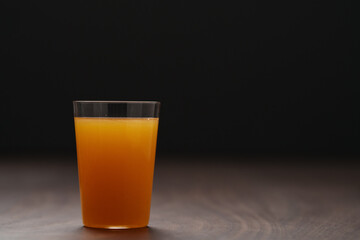 Fresh orange juice in thin glass on wooden table with copy space