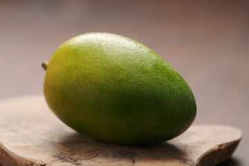 Ripe green mango washed and ready to eat on wood board