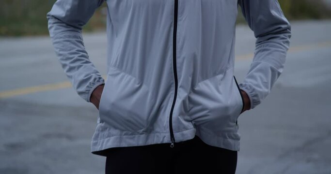 Slow-motion footage of a female opening her jacket's pockets and putting her hands inside
