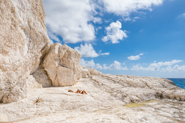 Couple sunbathe on the limestone rocky coast of Zakynthos island, Greece