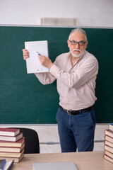 Old male teacher sitting in the classroom