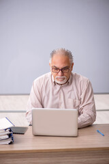 Old male teacher in front of whiteboard