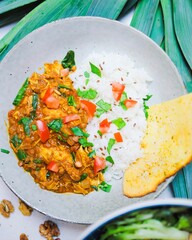 Vertical top view of an Indian curry meal served with rice on a glass plate