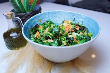 Closeup shot of an Italian healthy salad in a bowl, with an olive oil bottle next to it