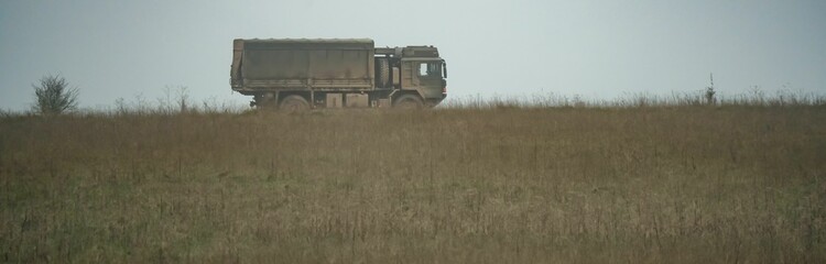 Fototapeta premium Military truck moving in a field