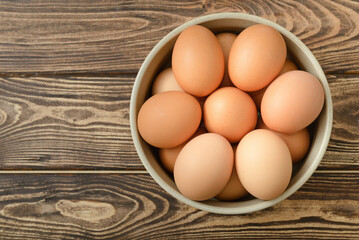 Top view of eggs in a bowl on wooden background