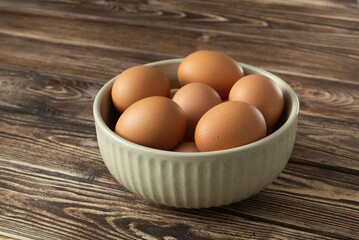 Uncooked eggs in a bowl on wooden background
