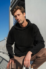 Serious young adult man on the street with blank space on his black hoodie