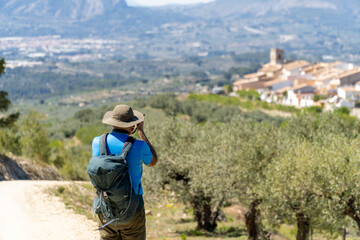 Hiker photographing a landscape with a beautiful town in the background