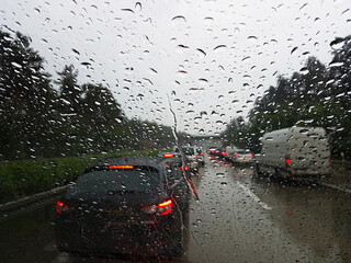 Abstract Traffic Jam in Raining Day, blurred background.,View from inside the car through windshield with rain drops.

