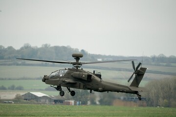 Military helicopter landing in a field