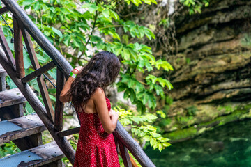 Naklejka premium Tourist in the stairway of the subway cenote Saamal of chichén itzá is in the Mayan jungle hacienda of the Yucatan Peninsula in Mexico, it is an ideal place for vacation.