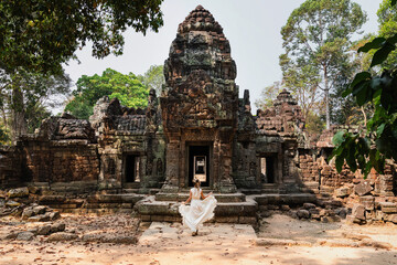 Naklejka premium Young woman wearing white robe dress in ancient Khmer ruins, Angkor Wat