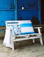 Wooden bench with blue and white pillows and a blanket on it