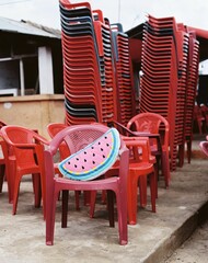 Vertical shot of red chairs stacked with watermelon pillow