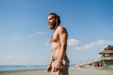 Fototapeta na wymiar Handsome bearded man with naked torso on the beach
