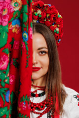 Portrait of ukrainian woman in traditional ethnic clothing and floral red wreath with handkerchief on viva magenta studio background. Ukrainian national embroidered dress call vyshyvanka