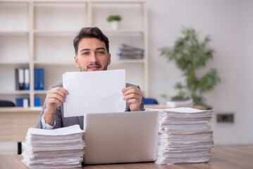 Young male employee and too much work in the office