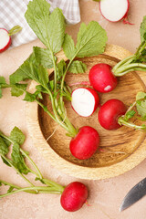 Ripe red radish in a wooden bowl on a beige background, top view. Fresh red radish. Vertically.