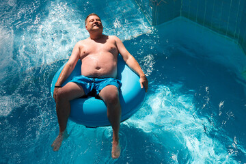 Adult man rides on an inflatable circle cheesecake in the water park.