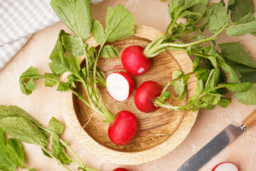 Ripe red radish in a wooden bowl on a beige background, top view. Fresh red radish.