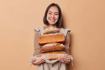 Happy Asian woman holds stack of loaves of bread on napkin demonstrates yeast free organic food...