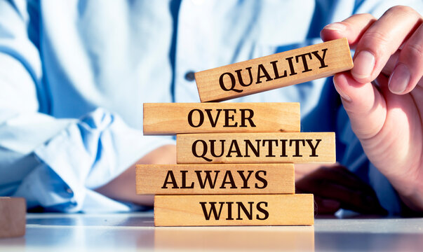 Close up on businessman holding a wooden block with "Quality over quantity always wins" message