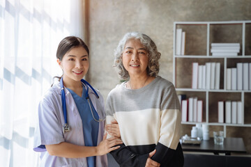 Female doctor and patient stand and smiling at camera, office interior on background.