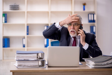 Old male employee sitting at workplace