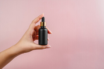 A young woman holds an essence in her hands. Oil for the health of the face. Anti-aging serum for...