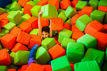 Fototapeta premium Girl playing in the dry pool with soft cubes.