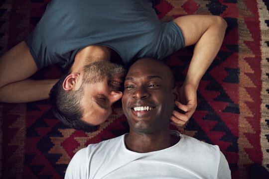 Smiling homosexual couple lying on floor together