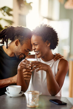 Affectionate African American couple laughing  over coffee in a cafe