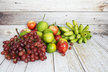 Various of fruits with Red grape, red apple, banana and green orange on wooden background