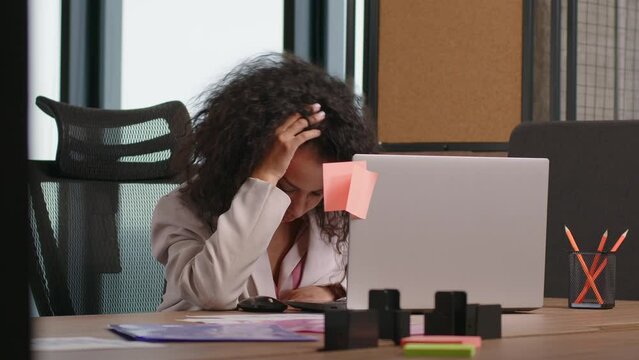 Overworked student girl worker sleeping at desk with laptop feels headache tired. Unproductive employee mixed race woman lying on table fall asleep feeling boredom