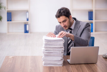 Obraz premium Young male employee and too much work in the office