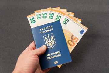 Passport of Ukraine and euro banknotes in hand. Monetary compensation, cash payments, assistance to Ukrainians abroad. Corruption and bribery in Ukraine.