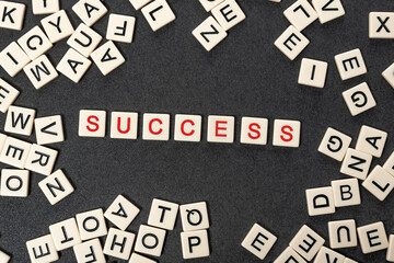 ++Red SUCCESS word written on white blocks surrounded by chaotic square tiles of letters alphabet.