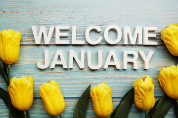 Welcome January alphabet letters with tulip flower on wooden background