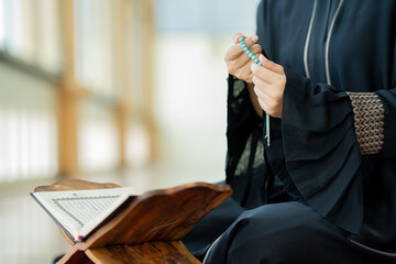 The image of an Asian Muslim woman in the Islamic religion in hijab in cream color. reading the Quran and having a happy smiling face Staying in a beautiful mosque out of respect for God.