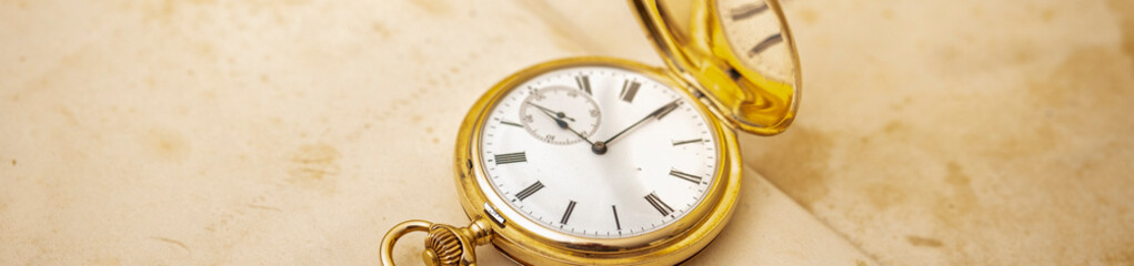 Vintage gold pocket watch on an open old book.