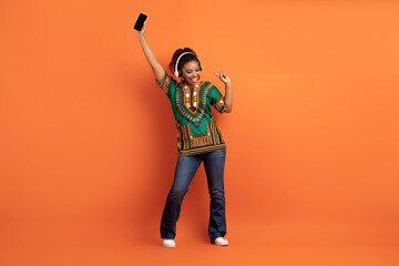 Fototapeta na wymiar Positive cool black woman enjoying nice music app
