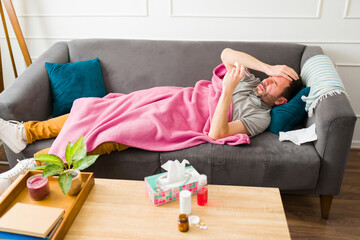 Pained sick man with a headache and fever resting on the couch