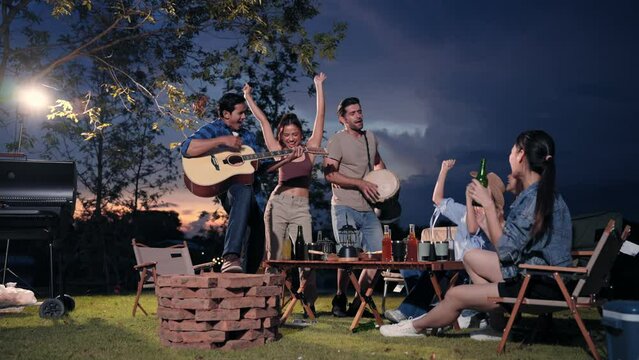 Happy young friends traveler group having fun music and dancing together in camping party, Group of multiculturalism hipster people enjoying holiday vacation trip in campsite