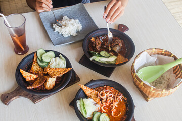 Sambal gami cumi or squid with sambal cooked in earthenware plate against wooden background. Served on wooden table